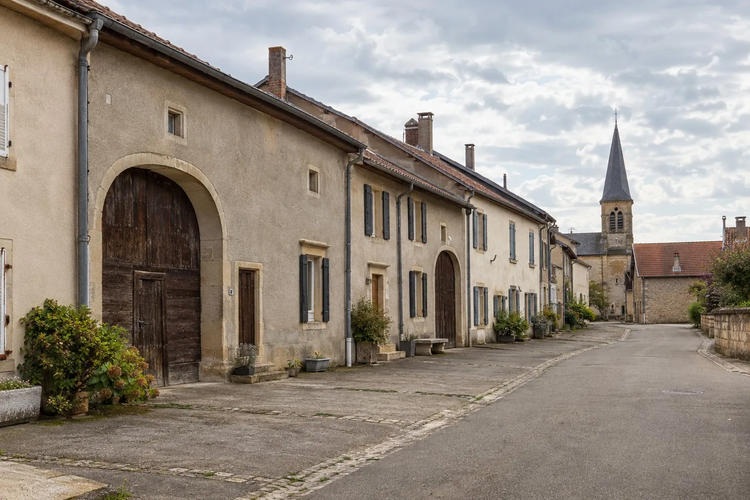 Rue d’un village lorrain de Moselle : maisons mitoyennes, portes charretières et usoirs
