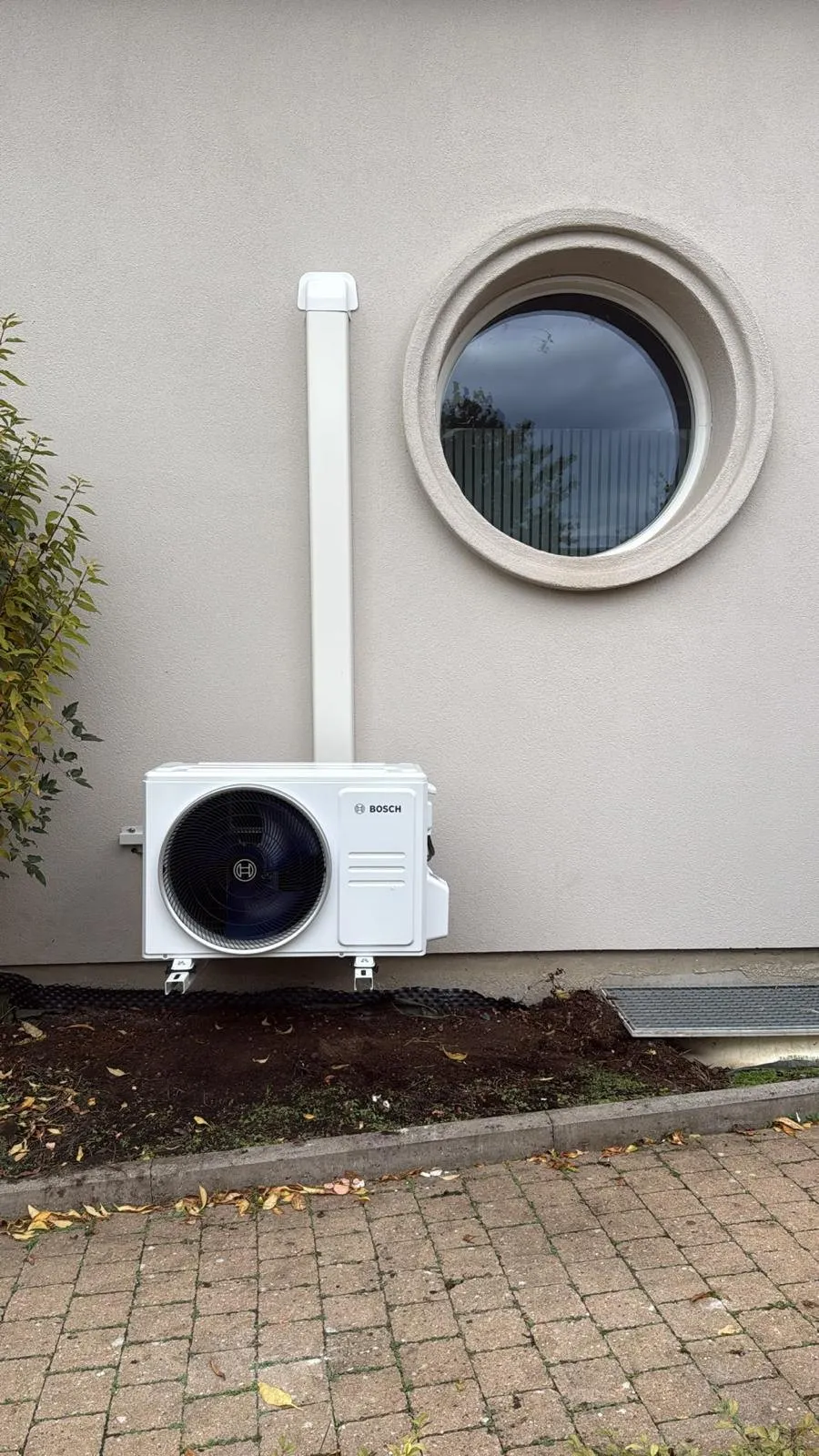 Unité extérieure de climatisation posée sous un hublot par REO Groupe, liaisons sous goulotte