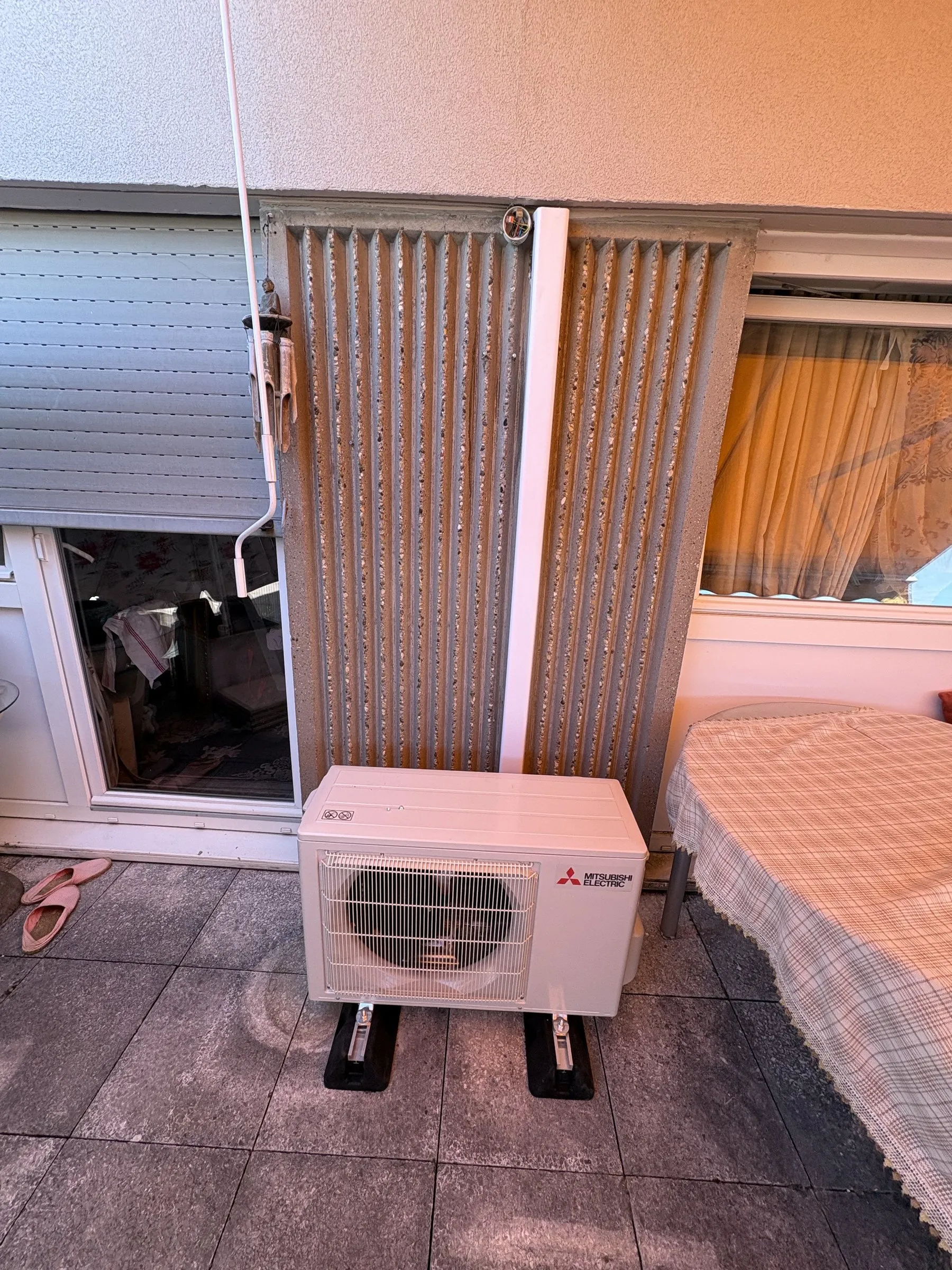 Unité extérieure Mitsubishi posée sur pieds sur une terrasse carrelée