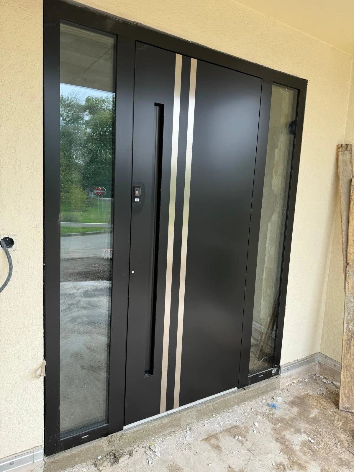 Porte d’entrée en aluminium noir avec poignée barre et vitrages latéraux