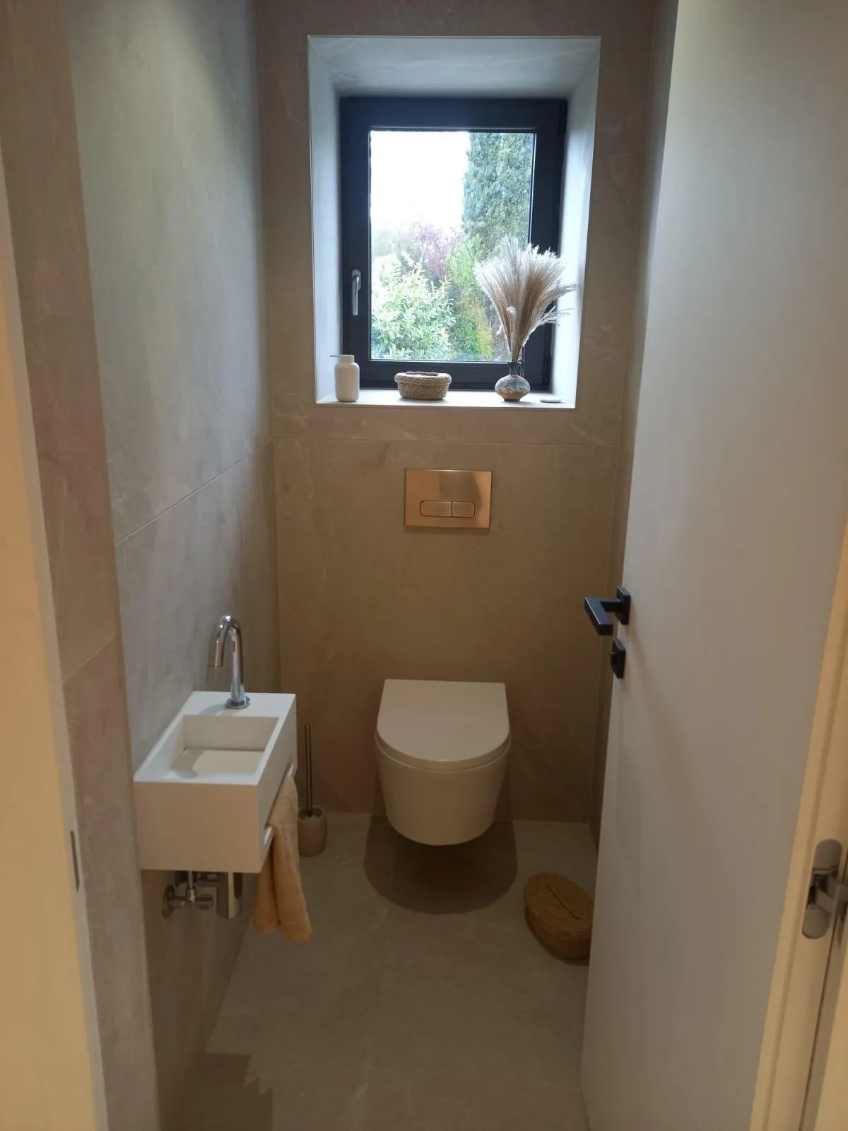 WC suspendu et lave-mains dans une pièce carrelée ton pierre