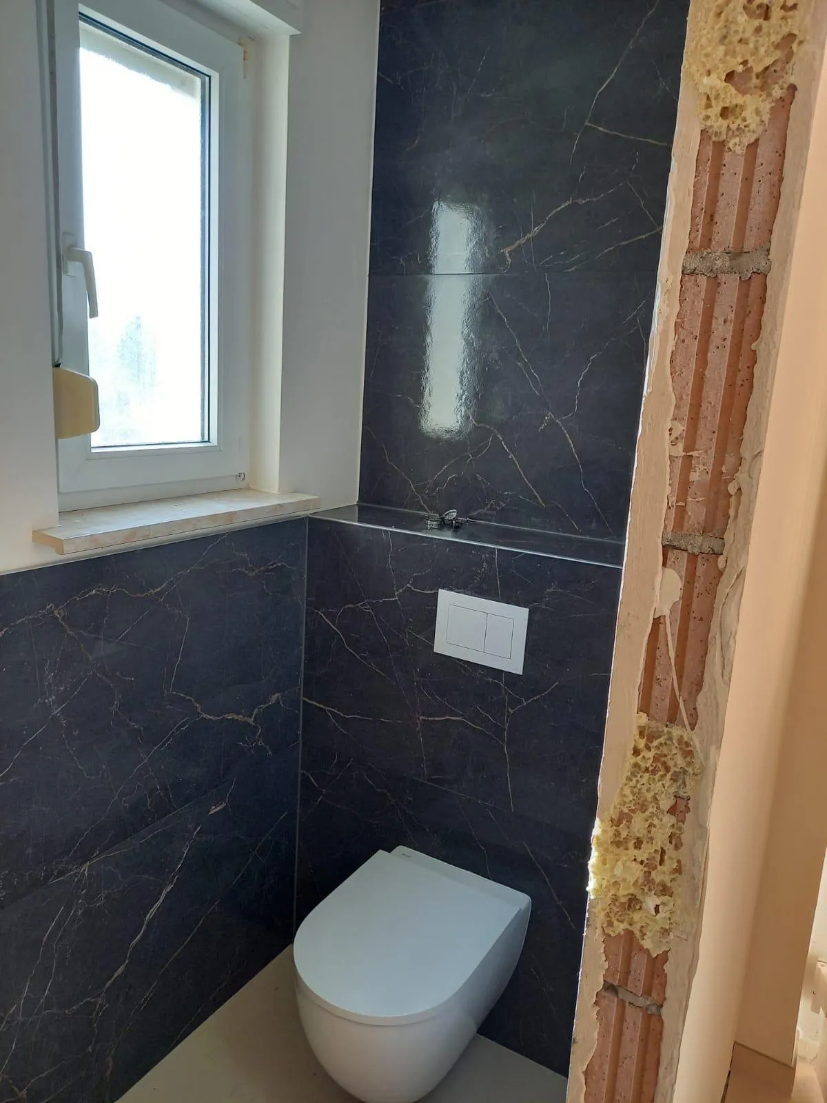 WC suspendu devant un carrelage grand format effet marbre noir